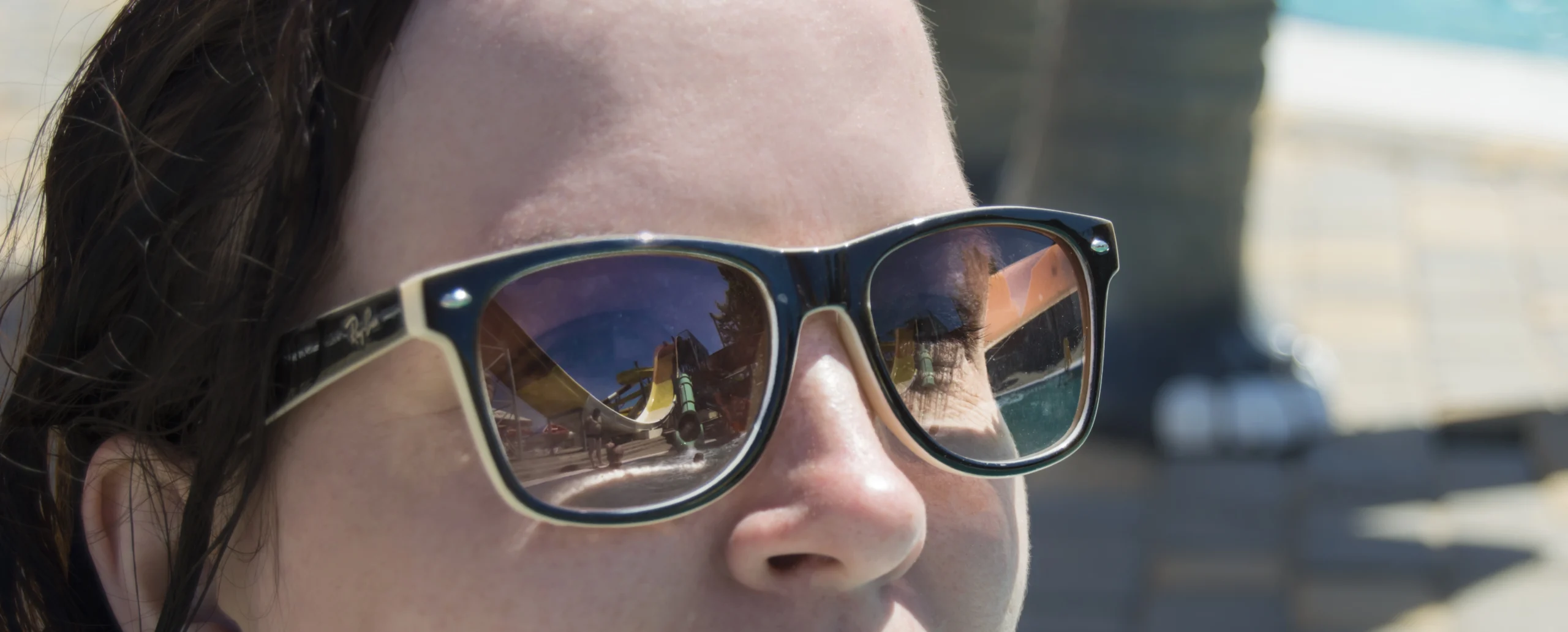 Primer plano de una persona con lentes de sol Ray-Ban junto a una piscina